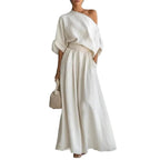 White one-shoulder top and maxi skirt set shown on plain background, highlighting the draped neckline and gathered waistband
