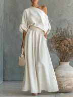 Three-quarter view of white one-shoulder maxi set showing the fitted waistband and A-line skirt silhouette with pockets