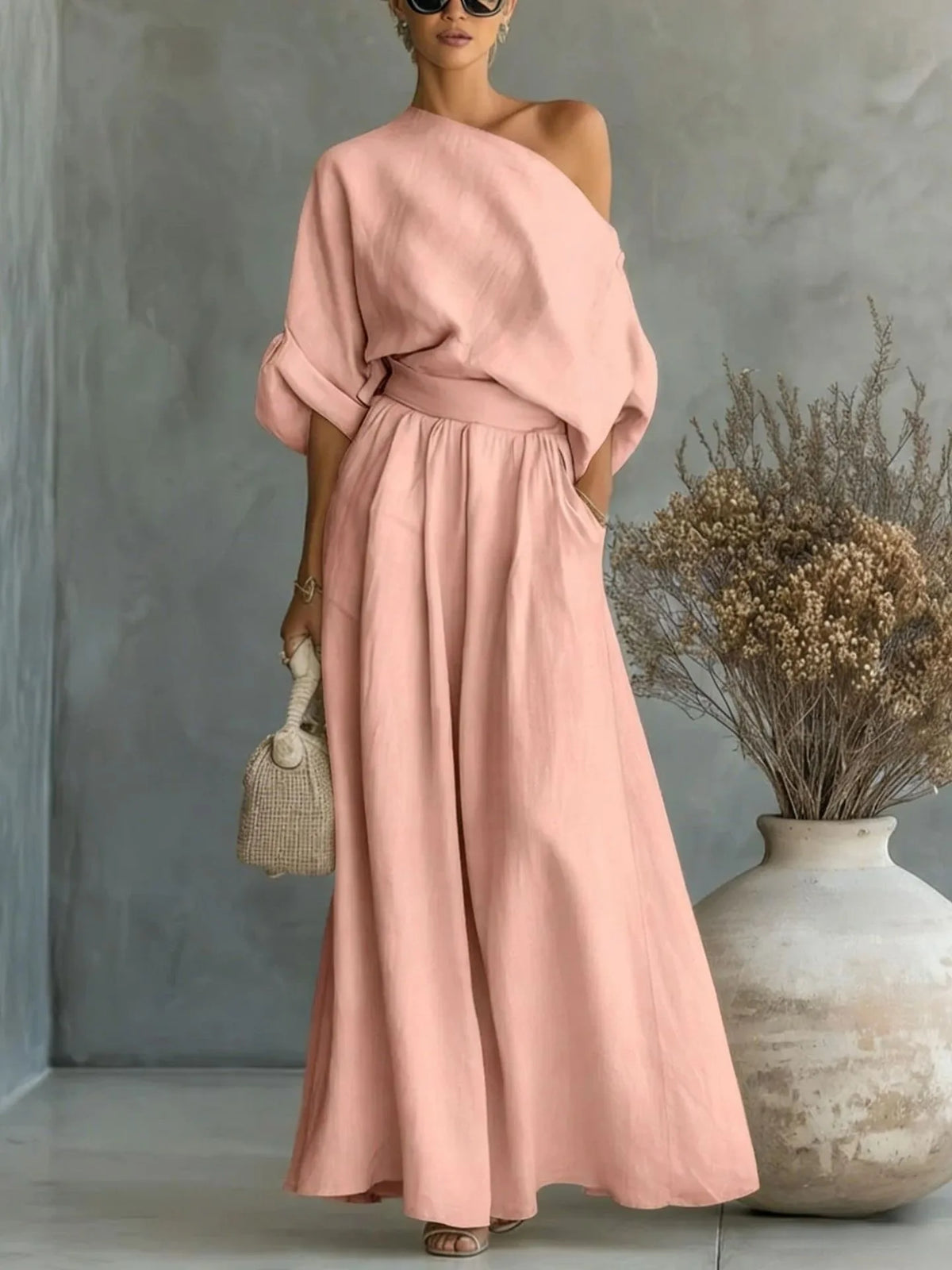 Close-up of the asymmetric one-shoulder neckline and cuffed sleeve on the black linen-look top