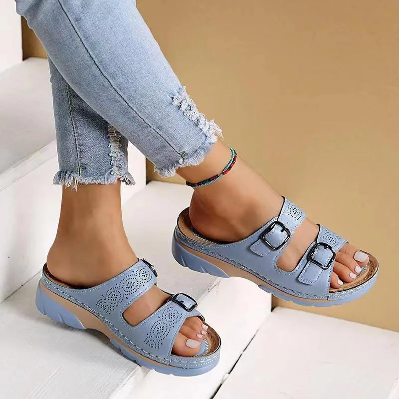 Light blue wedge sandal with open toe and buckle straps, shown on stairs highlighting the platform sole and stitched trim