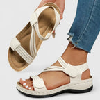 White strappy sandal held up revealing contoured padded insole with stitched arch support detail