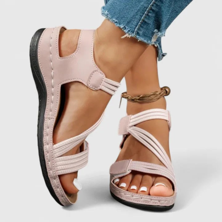 Side view of pink sandal worn on foot showing crisscross straps and chunky comfort sole