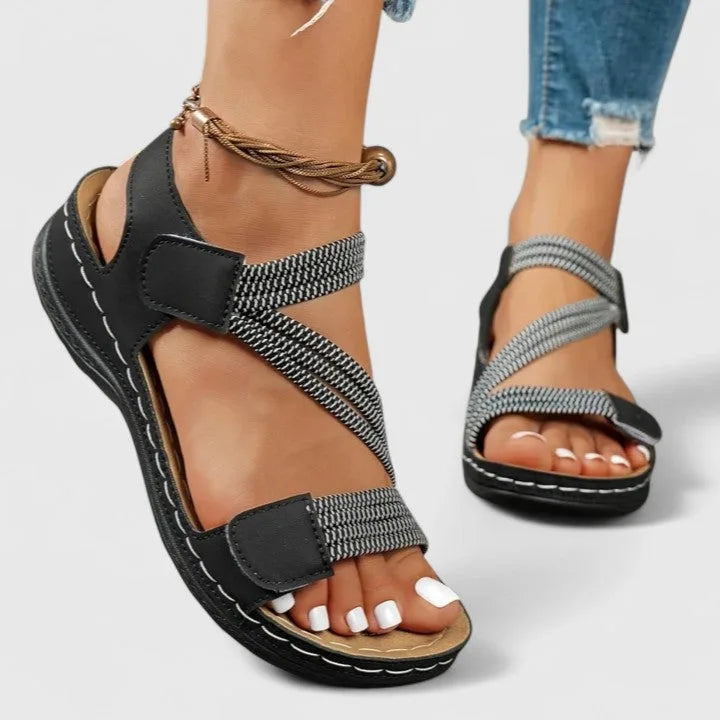 Black and white woven strap sandal worn on foot with hook and loop ankle closure