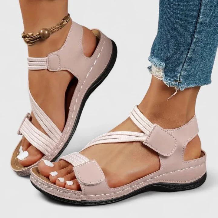Pink sandal pair worn showing cutout heel design and adjustable touch strap closure