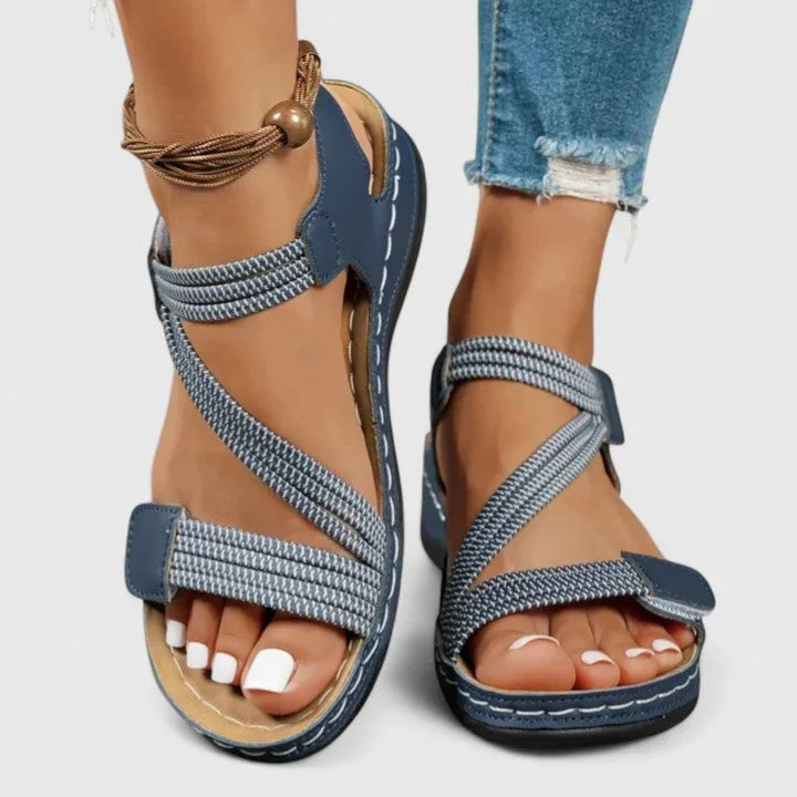 Blue and white woven strap sandal worn on feet with crossover front straps