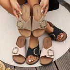 Side view of black crossover sandals on feet walking, showing the cork platform sole and brass buckle from the front