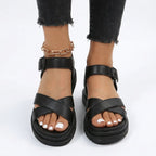 Black cross-strap platform sandals with matching buckle ankle strap and black ribbed outsole, shown from the front
