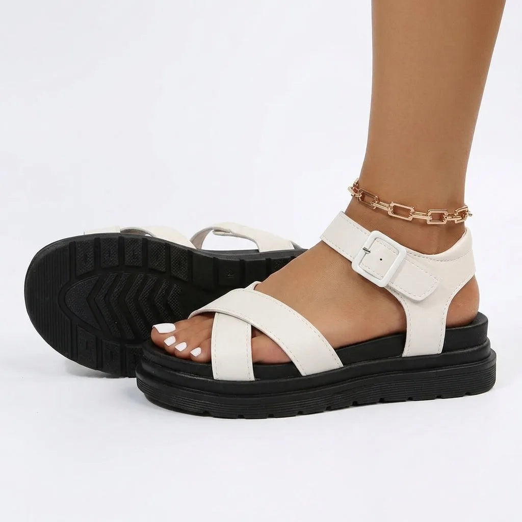 Side and sole view of cream white platform sandals showing the ribbed black tread and buckle ankle strap