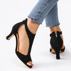 Back view of black suede cut-out heels showing ankle buckle strap and rear zip closure detail