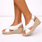 White espadrille wedge sandal with buckle ankle strap, side view showing the slingback heel and jute platform.