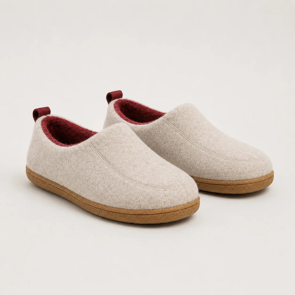 Pair of beige felt slip-on slippers with burgundy fleece trim and lining, shown from the front angle