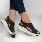 Woman wearing charcoal grey knit sandals with jeans, showing open heel and chunky white sole from the side