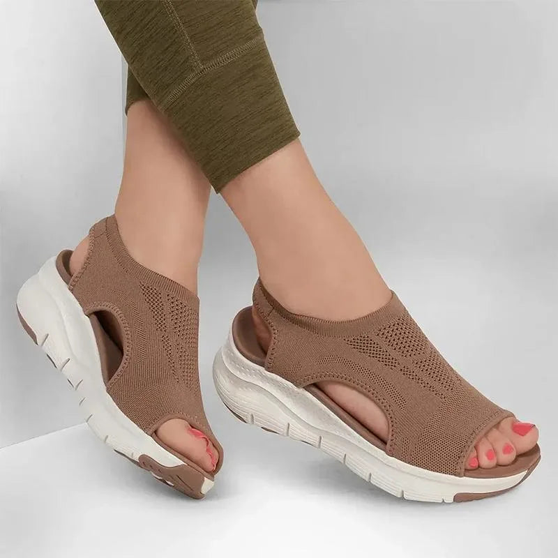 Woman wearing tan brown knit sandals with leggings, front angle showing open toe and platform sole