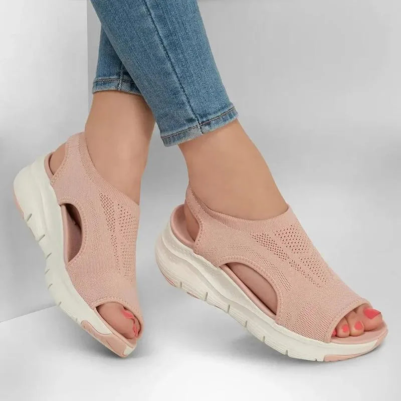 Woman wearing blush pink knit sandals with jeans, close-up on the cushioned footbed and sling-back strap