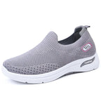 Side view of grey knit slip-on sneaker with pink accent logo tab and thick white midsole