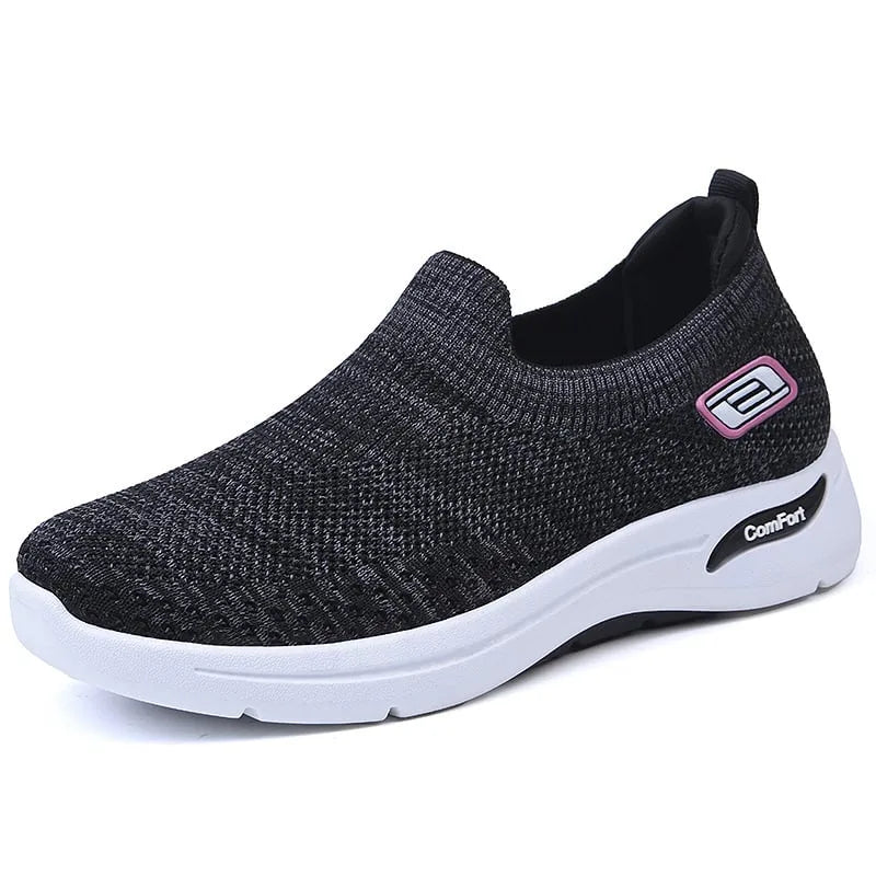 Side view of black knit slip-on sneaker with pink and white logo detail and white contrast sole
