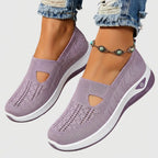 Close-up side view of dusty purple knitted slip-on sneakers with cut-out detail and white chunky sole, worn with ripped jeans