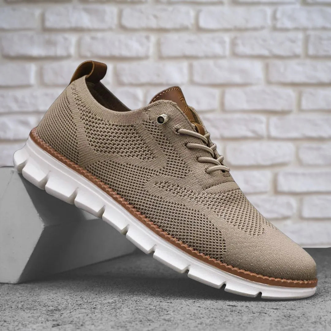 Beige knit lace-up sneaker resting on a concrete block, showing tan heel tab and white sole