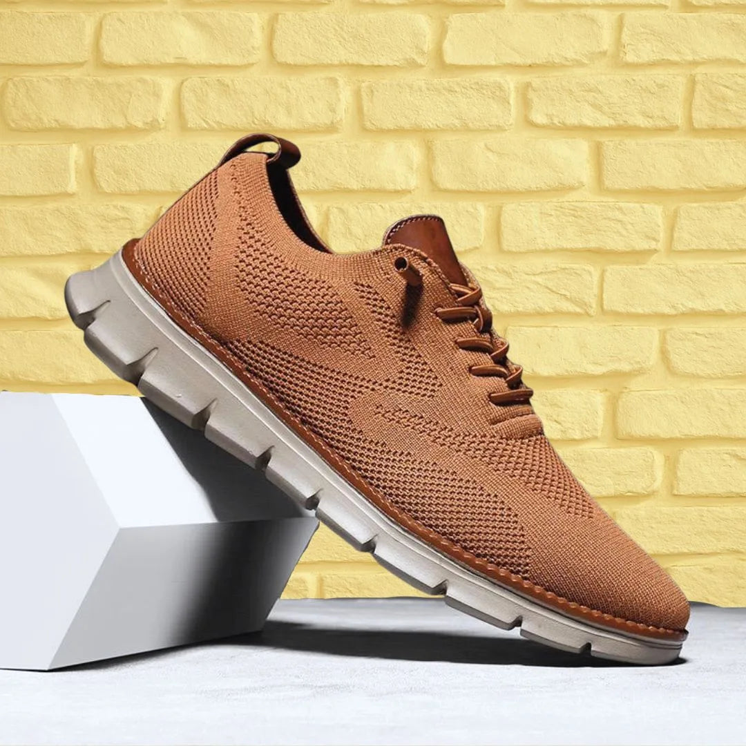 Caramel brown knit sneaker against a yellow brick wall, showing contrast cream outsole and tan trim