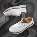 Pair of white knit sneakers laid flat on a grey marble surface showing top and side views
