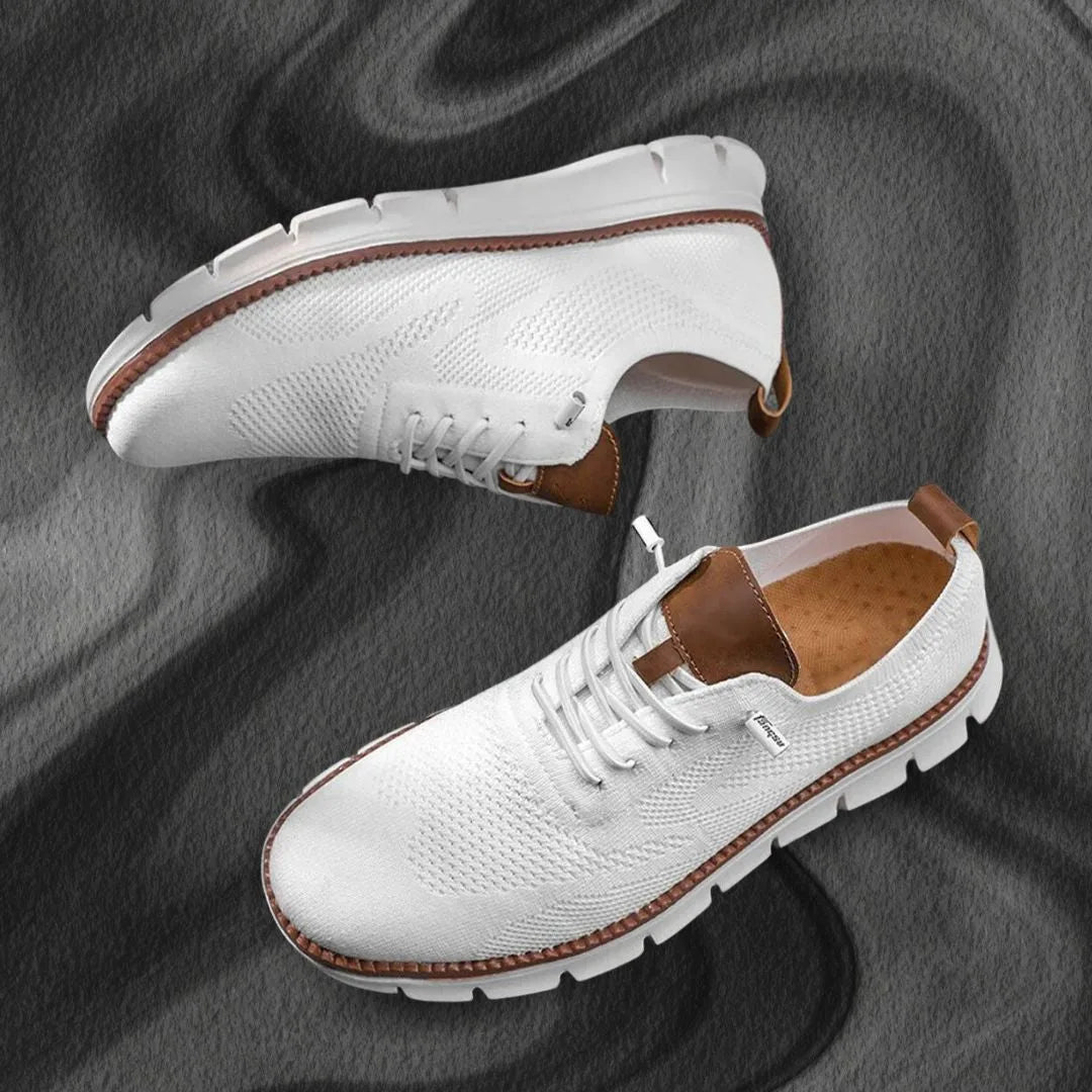 Pair of white knit sneakers laid flat on a grey marble surface showing top and side views