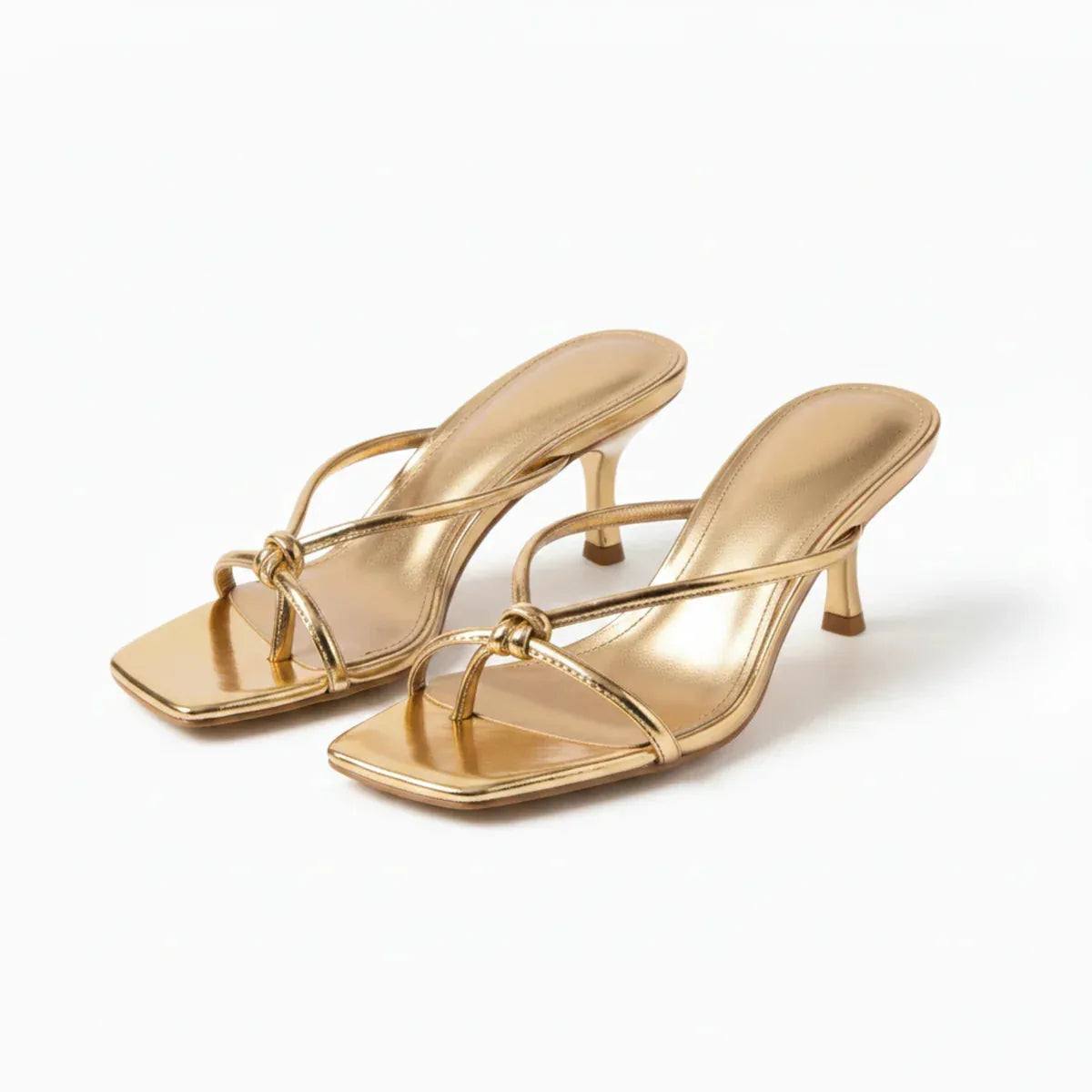 Pair of gold metallic strappy heeled sandals with knot detail, angled front view