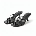 Pair of black strappy heeled sandals with knot detail, angled view on plain background