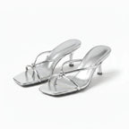 Pair of silver metallic strappy heeled sandals with knot detail, angled front view