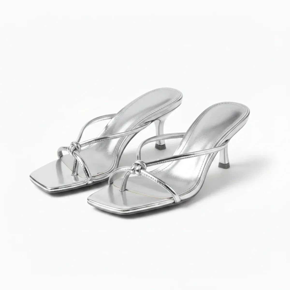 Pair of silver metallic strappy heeled sandals with knot detail, angled front view