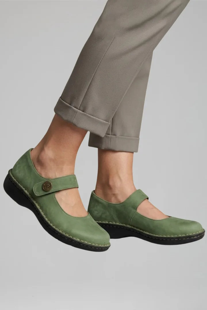 Side profile of a foot stepping forward in a green nubuck Mary Jane flat with button strap