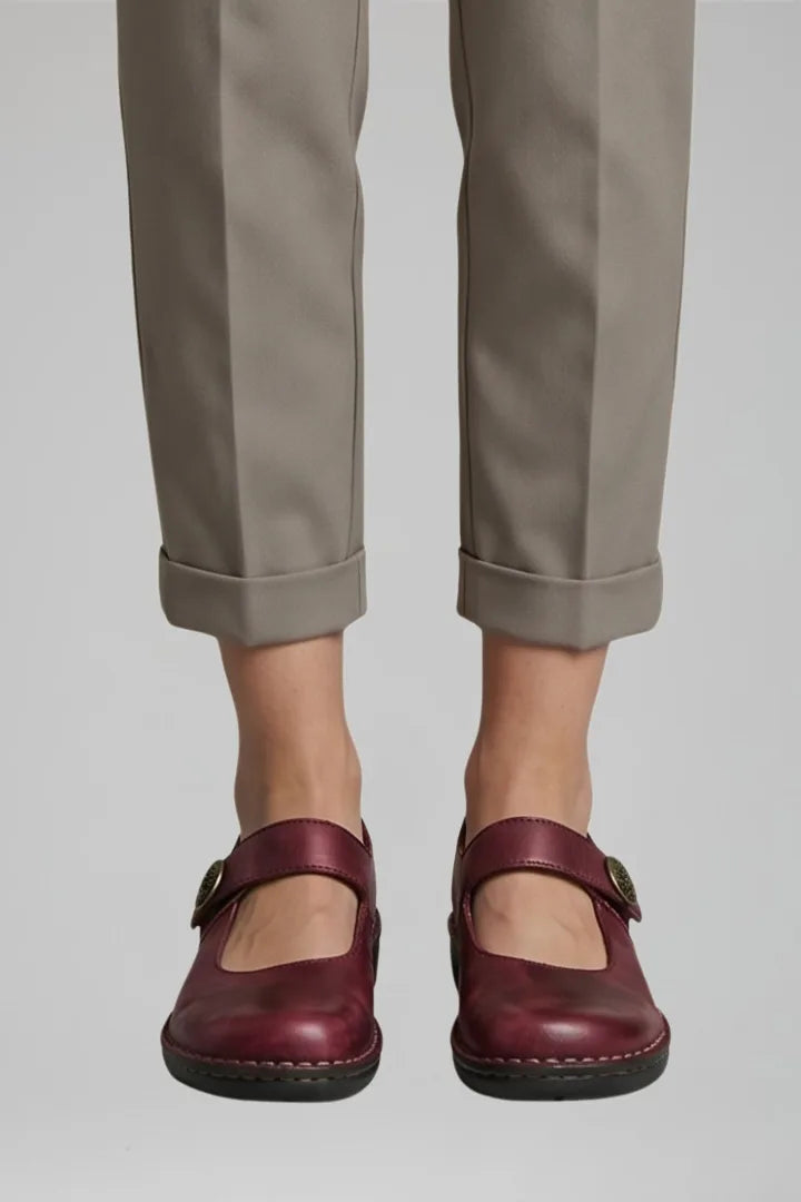 Close-up front view of burgundy leather Mary Jane flats with button strap and cuffed trousers