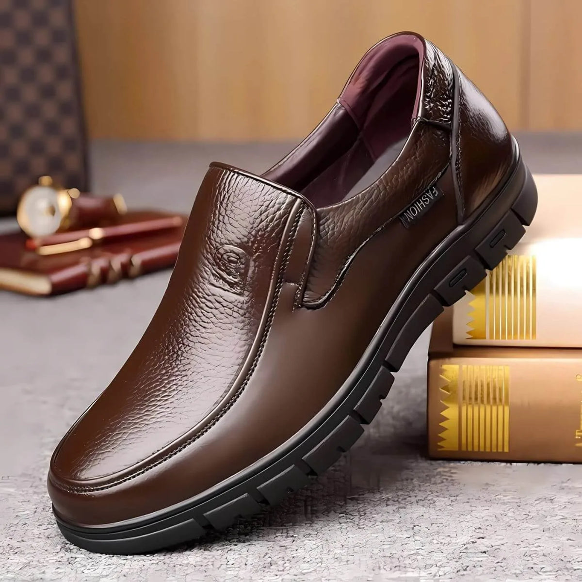 Angled view of brown leather slip-on shoe with glossy pebbled finish resting against stacked books, showing ridged sole