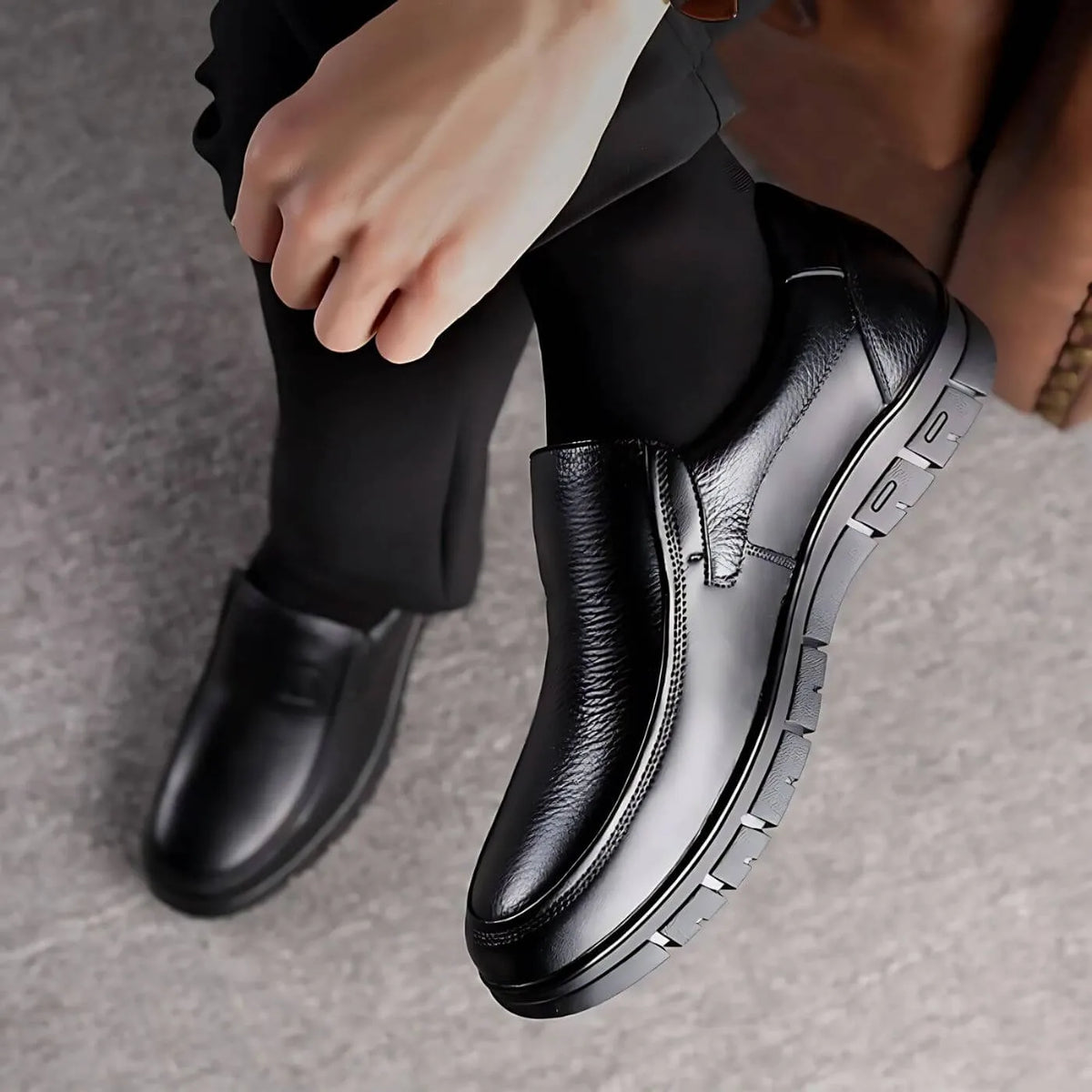 Overhead view of black leather slip-on shoes being worn, highlighting the textured upper and segmented rubber outsole