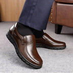 Walking shot of brown leather slip-on shoes paired with dark trousers, showing the smooth vamp and low-profile heel