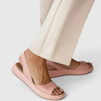 Side view of blush pink slingback sandal with peep toe and chunky platform sole, worn with cream wide-leg pants