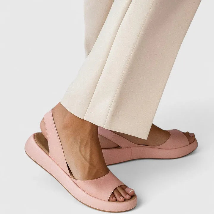 Side view of blush pink slingback sandal with peep toe and chunky platform sole, worn with cream wide-leg pants