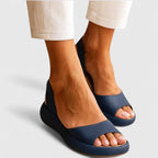 Navy blue peep-toe platform sandals worn with cream trousers, showing thick cushioned sole from the front