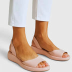 Blush pink slingback platform sandals shown from the side against white cropped trousers