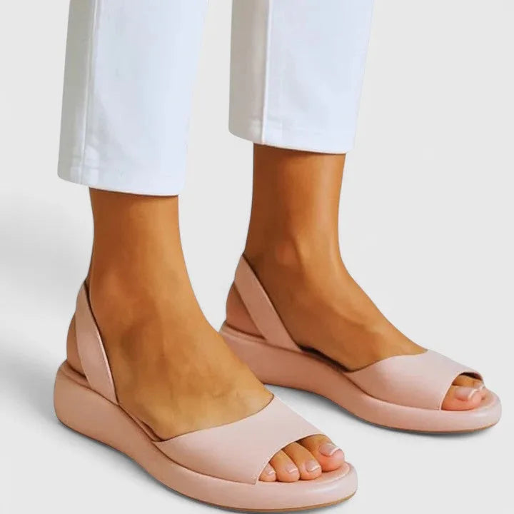 Blush pink slingback platform sandals shown from the side against white cropped trousers