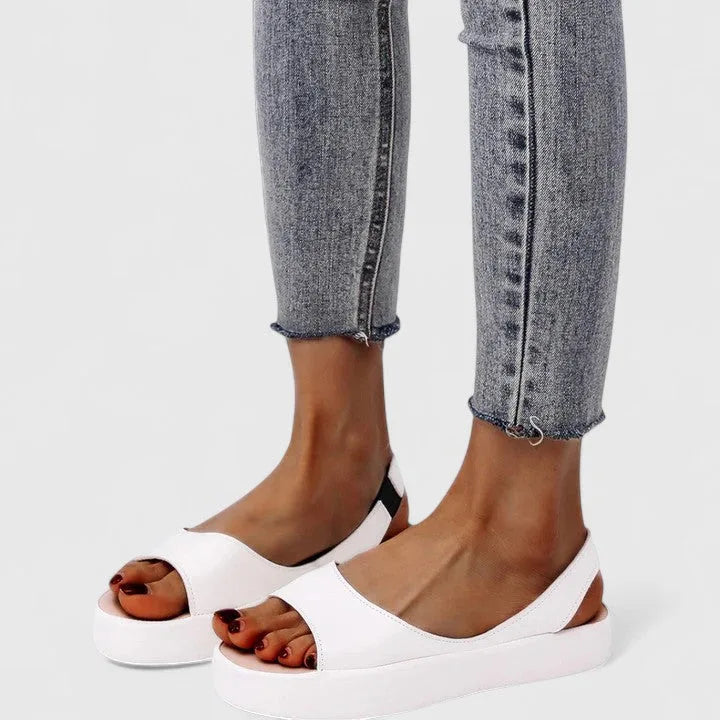 White slingback platform sandals worn with grey frayed-hem jeans, showing clean rounded toe