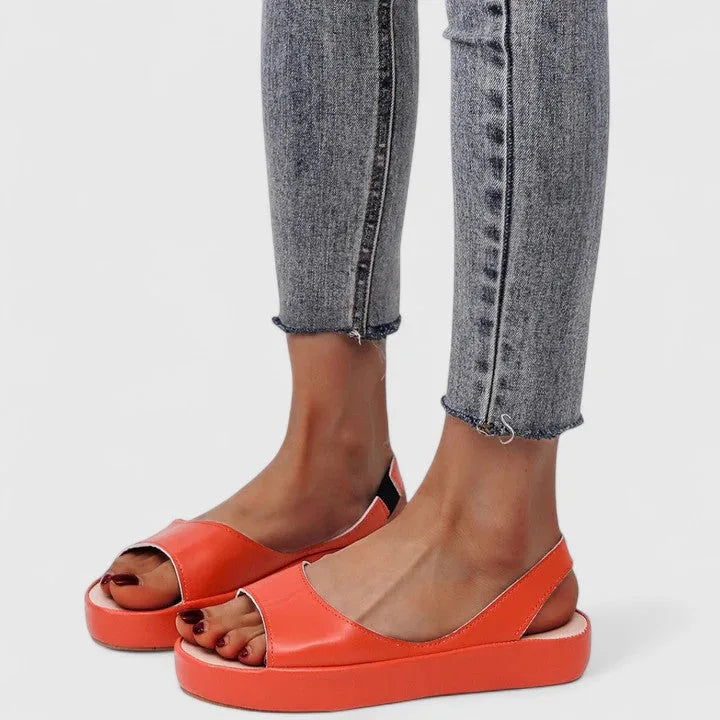 Orange slingback platform sandals shown front-on with grey skinny jeans and painted toenails