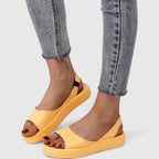Yellow slingback platform sandals paired with grey jeans, showing elastic back strap detail