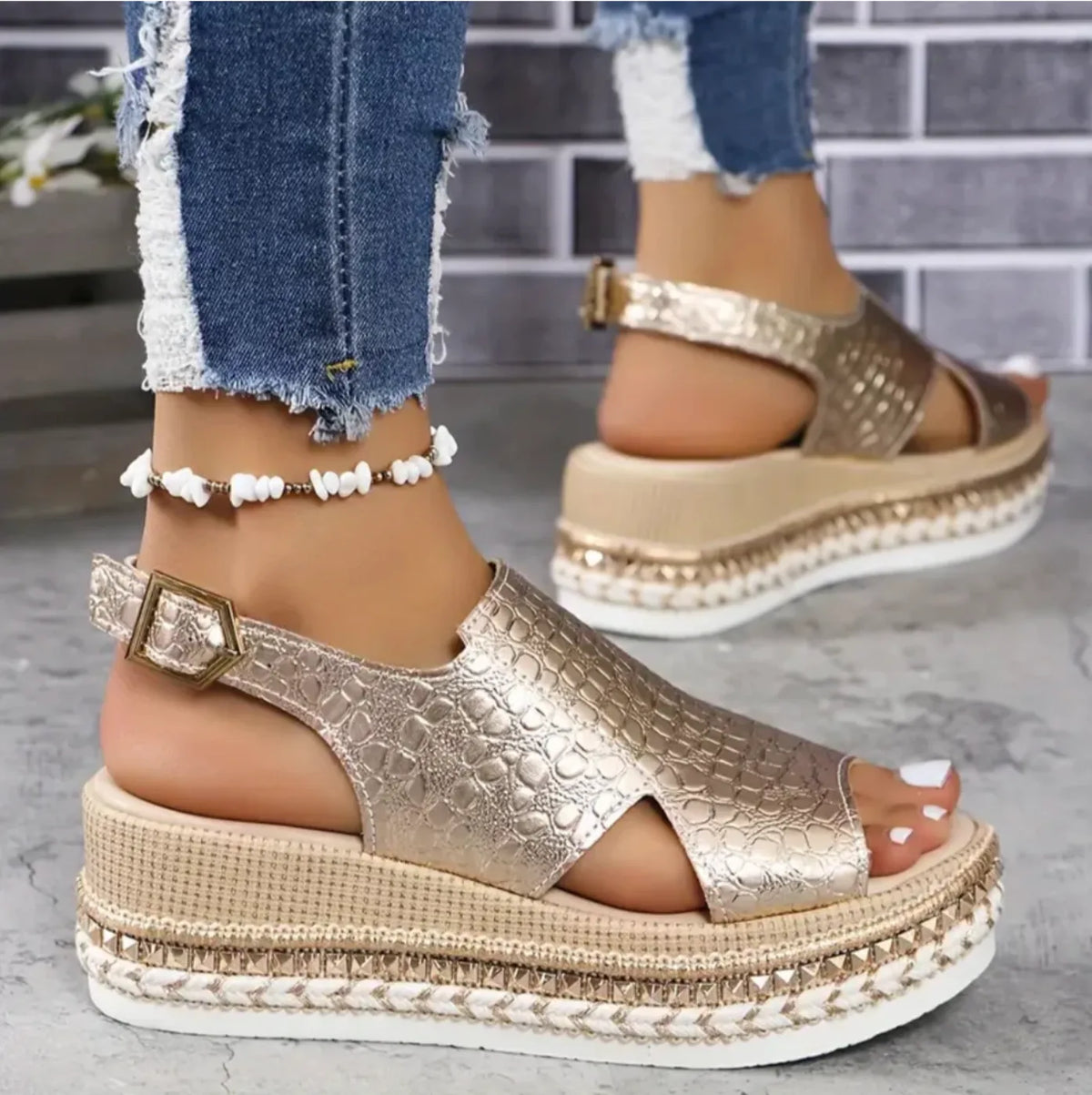 Model wearing gold textured wedge sandals with ripped jeans, showing slingback strap and ankle buckle detail