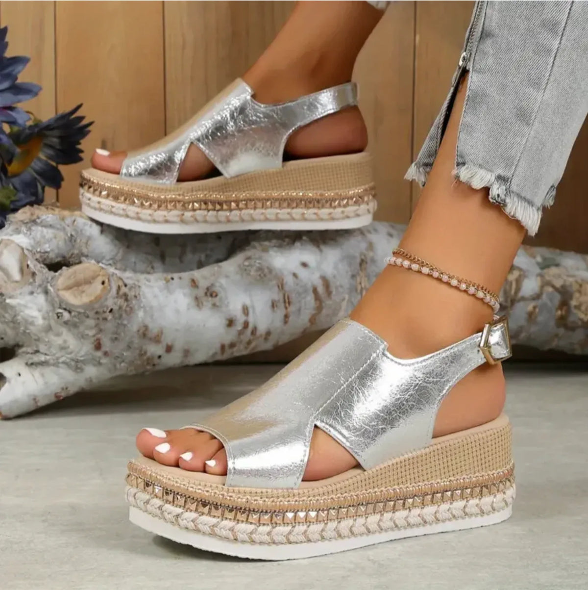 Model standing in metallic silver crinkled leather platform wedge sandals with open toe and ankle strap