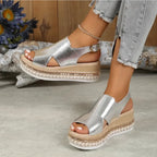 Side angle of silver metallic wedge sandal on foot, highlighting the woven platform sole and slingback buckle