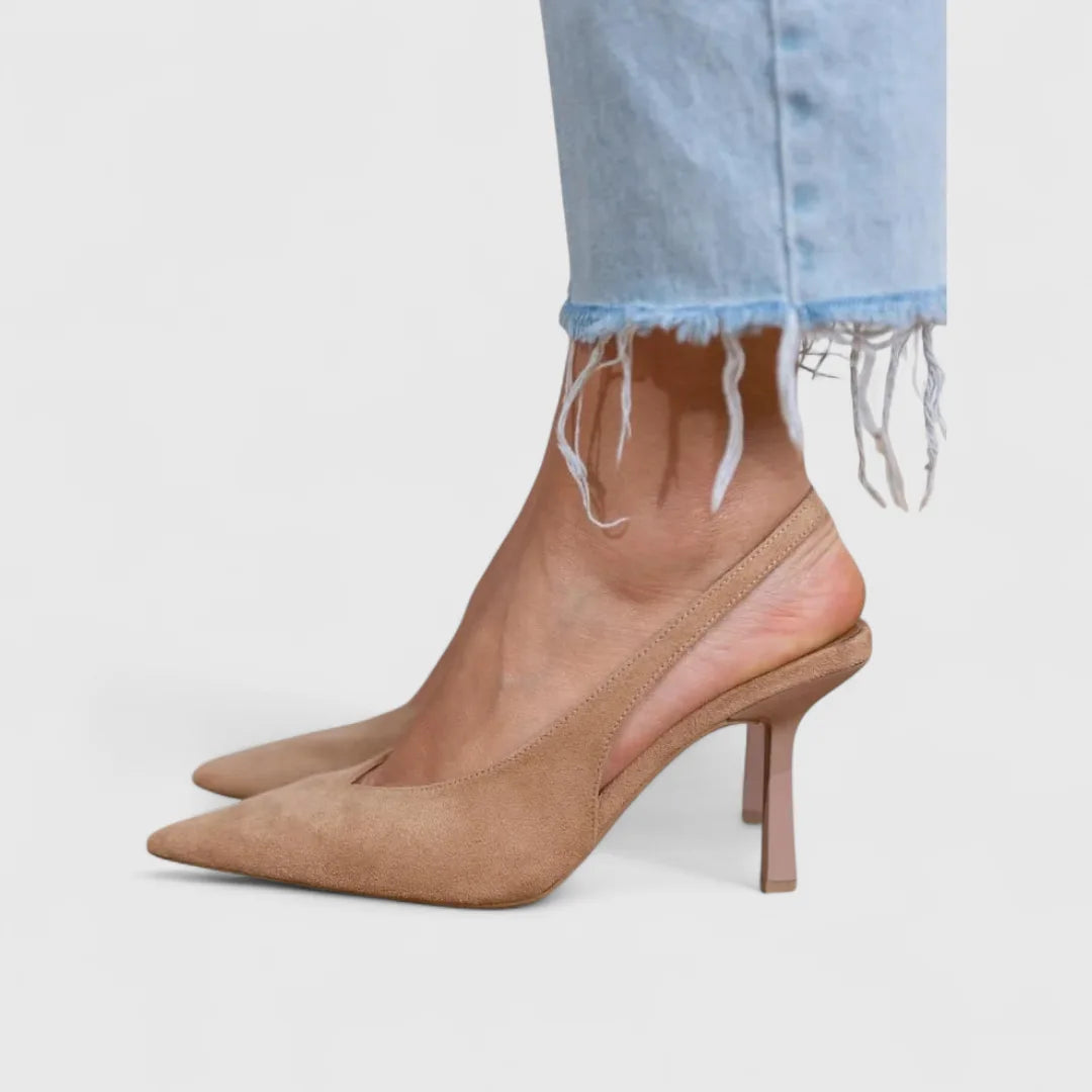 Side view of beige suede slingback heels worn with light-wash frayed-hem jeans, pointed toe detail