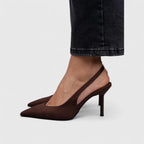 Close-up of dark brown suede slingback pumps with slim heel, worn with charcoal denim