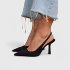 Black slingback pumps in a matte fabric finish, pointed toe, shown with light denim jeans
