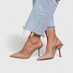 Nude leather slingback pumps shown mid-step, highlighting the pointed toe and slender heel