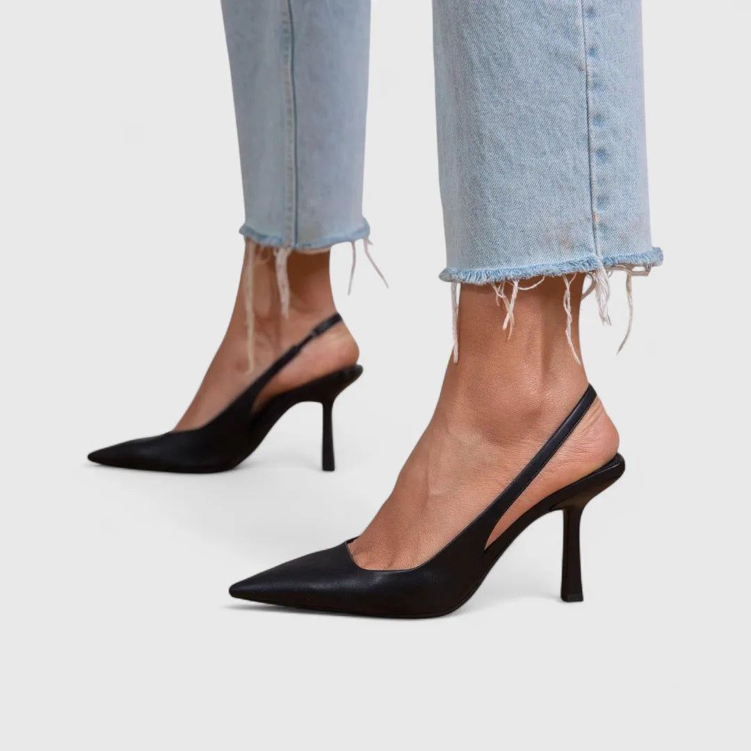 Black leather slingback heels with pointed toe, close-up side profile against light-wash denim